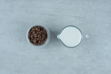 Obraz na płótnie Canvas A glass cup of milk with coffee beans on white background