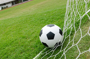 The soccer football with the net on the artificial green grass soccer field