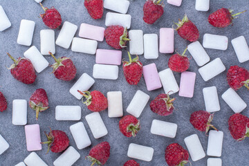 Raspberries thrown into a mess of gum tablets on marble background