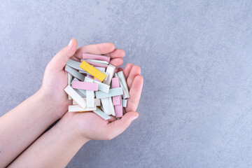 Hands full of bubblegum strips on marble background
