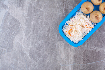 Sauerkraut and pickled fruits on blue plate