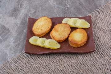 Fried potato slices and pickled cucumbers on plate