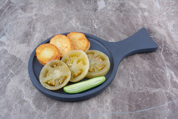 Fried potato slices and pickled tomatoes on plate