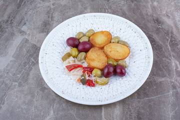 Roasted potato and various pickles on white plate