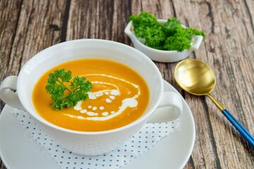 Pumpkin soup with coconut milk with parsley. Wooden background