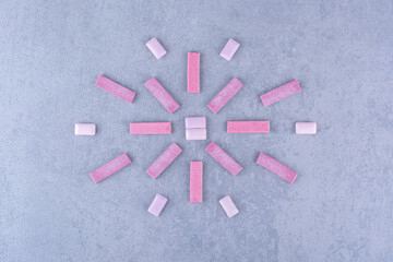 Chewing gum sticks and tablets neatly arranged into a motif on marble background