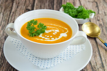 Pumpkin soup with coconut milk with parsley. Wooden background