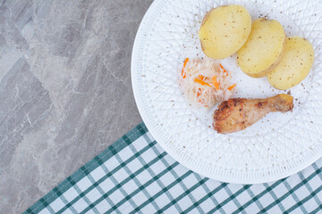 Grilled chicken leg, potato and sauerkraut on white plate