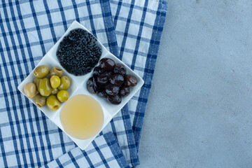Pitless olives, honey and caviar on marble background