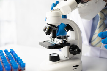 Doctor hand taking a blood sample tube from a rack with machines of analysis in the lab background, Technician holding blood tube test in the research laboratory.