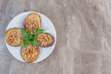 A delectable serving of indian eggplant fried and seasoned with garlic, adorned with parsley on marble background