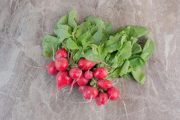 Fresh bunch of red turnips and turnip leaves on marble background