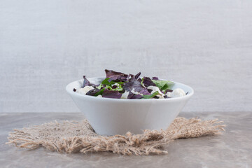 Appetizing light salad mix of amaranth, basil leaves and cauliflower in a bowl on marble background