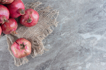 Stack of pomegranates on a piece of cloth on marble background