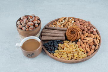 A cup of coffee with various nuts and cookies