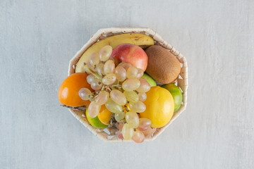 A wicker basket full of sweet fruits on white background
