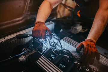 auto mechanic repairs the car, removes the valve cover, unscrews the bolts.