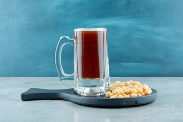 A glass of beer with peas on dark cutting board