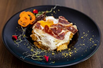 Closeup of delicious huevos rotos. A Spanish dish with fried eggs, potatoes, and meat.