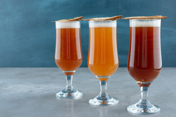 Three glasses of light beer with fish on gray background