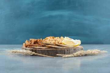 A wooden board with delicious snacks and wheat
