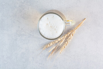 A glass of delicious beer with wheat on hay background