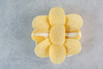 A white plate of crunchy potato chips on gray background