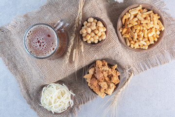 Fototapeta na wymiar A mug of beer with breadsticks and peas on sackcloth