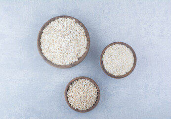 Assortment of white grain products filled into wooden bowls, on marble background