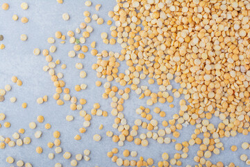 Yellow lentil messily scattered over marble background