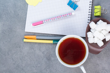 A cup of delicious tea with pencils and sheet of paper