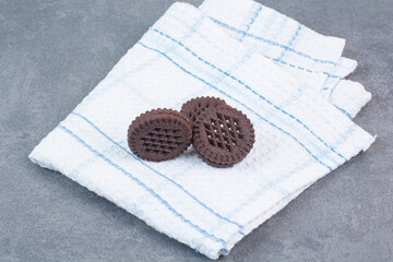 Three chocolate cookies lying on tablecloth