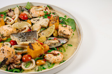 Dish of boiled dorada fish with shellfish, vegetables and herbs