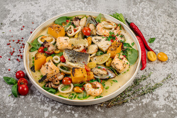 Dish of boiled dorada fish with shellfish, vegetables and herbs