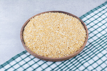 Large wooden tray full of brown rice on marble background
