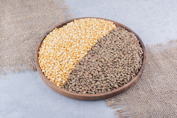Large wooden tray filled with brown and red lentil on marble background