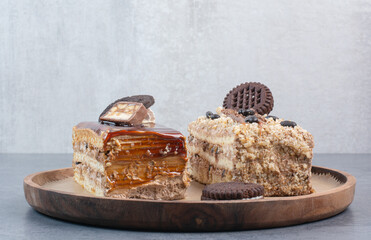 Two sweet delicious piece of cakes with cookies on wooden board