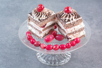 Two sweet delicious piece of cakes with rosehips on glass plate