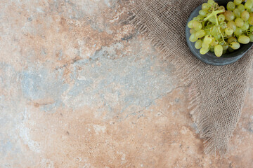 An ancient cup full of sweet grapes on marble background
