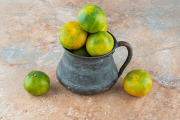 An ancient cup with sour tangerines on marble background