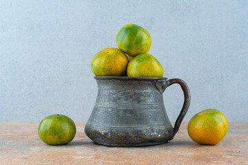 An ancient cup with sour tangerines on marble background