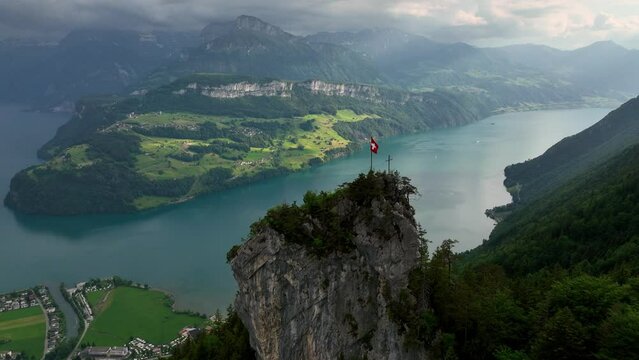 flying above beautiful Lake Lucerne, alpine lake in Switzerland with Swiss flag on a rock, panoramic view of Luzern lake, tourism in Switzerland