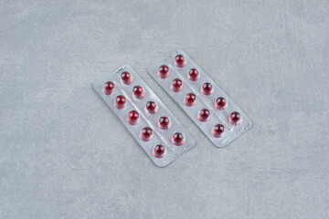 Packing oval red medicine pills on gray background