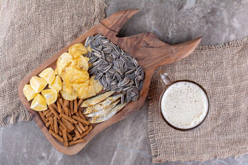 Glass of beer and wooden board of snacks