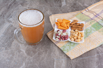 Plate of variety of snack and beer on marble surface