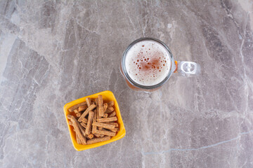 Crackers and glass of cold beer on marble surface