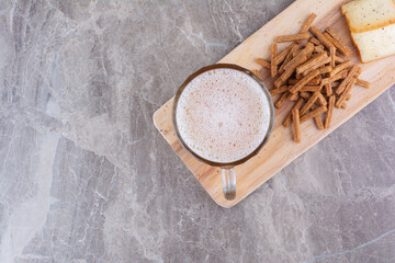 Crackers, cheese and glass of beer on wooden board