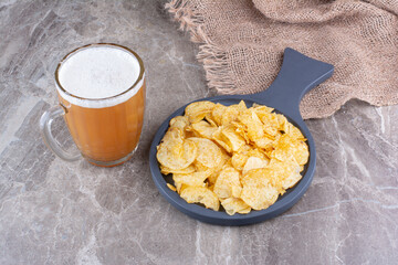 Crispy chips on dark board with glass of beer