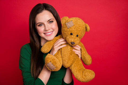 Photo portrait of adorable woman hairdo arms hold teady bear dressed stylish green long sleeve shirt isolated on shine red color background