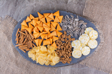 Assortment of delicious snacks on wooden piece